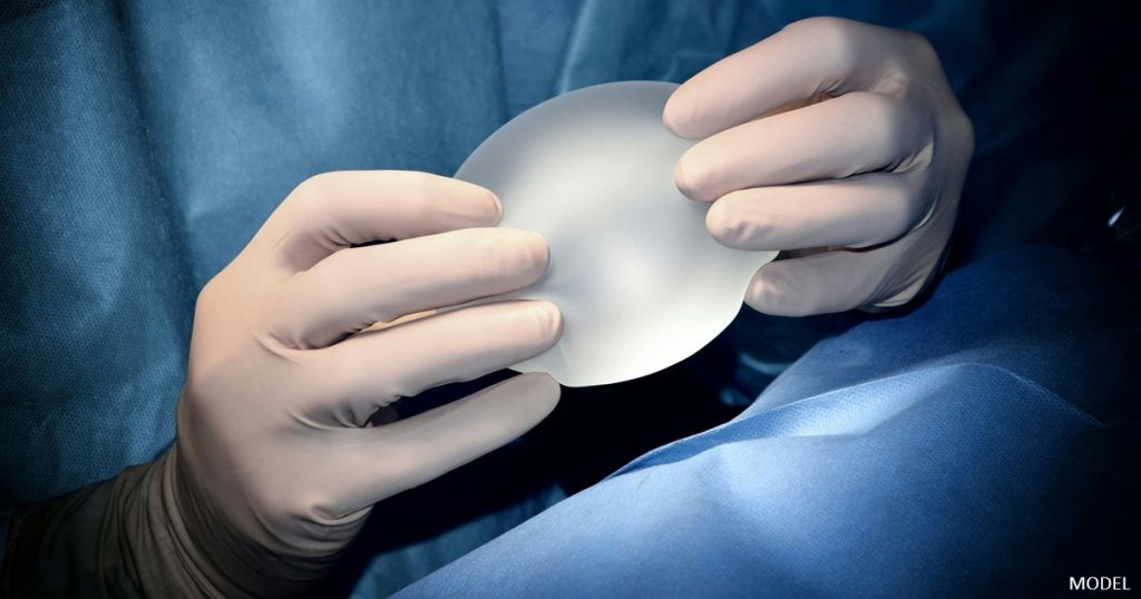 Surgeon holding a breast implant